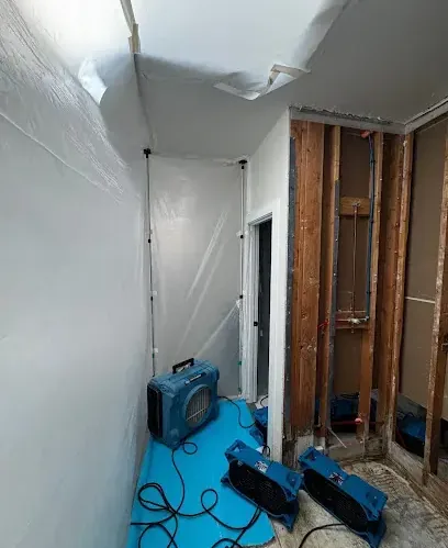 Plastic containment and air movers drying an opened wall cavity
