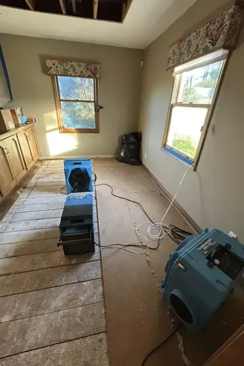 An air mover and a dehumidifier drying a bedroom subfloor