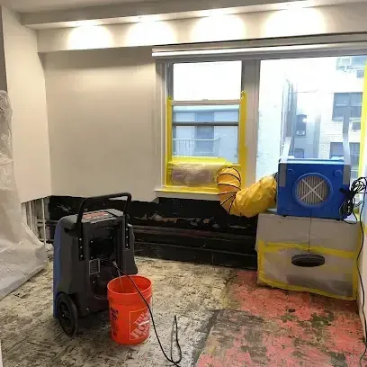 Crew in protective gear removing wet carpet from a basement