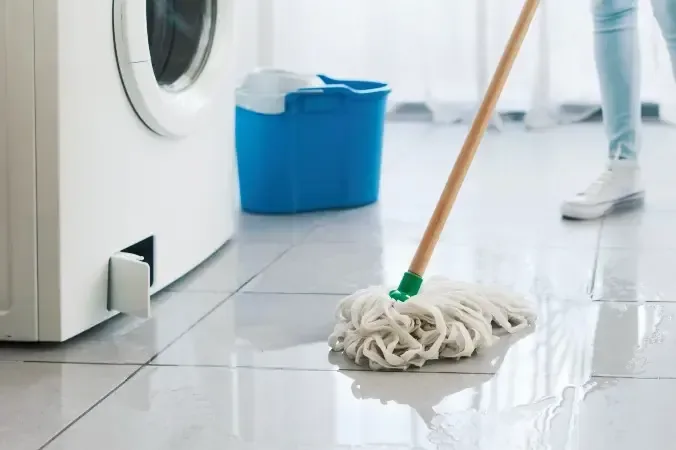 Water spreading over a tile floor from a leaking washing machine